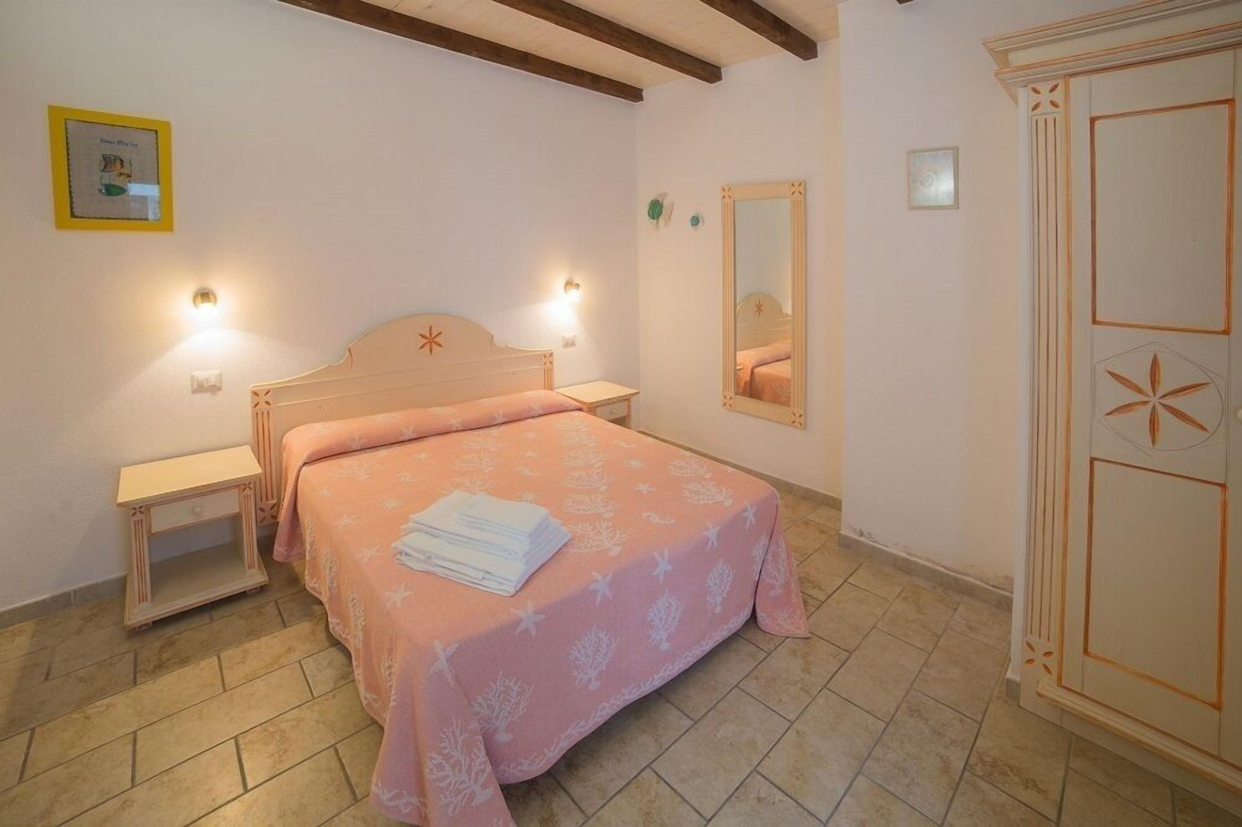 Un dormitorio con cama, mesitas de noche, un espejo y un armario.