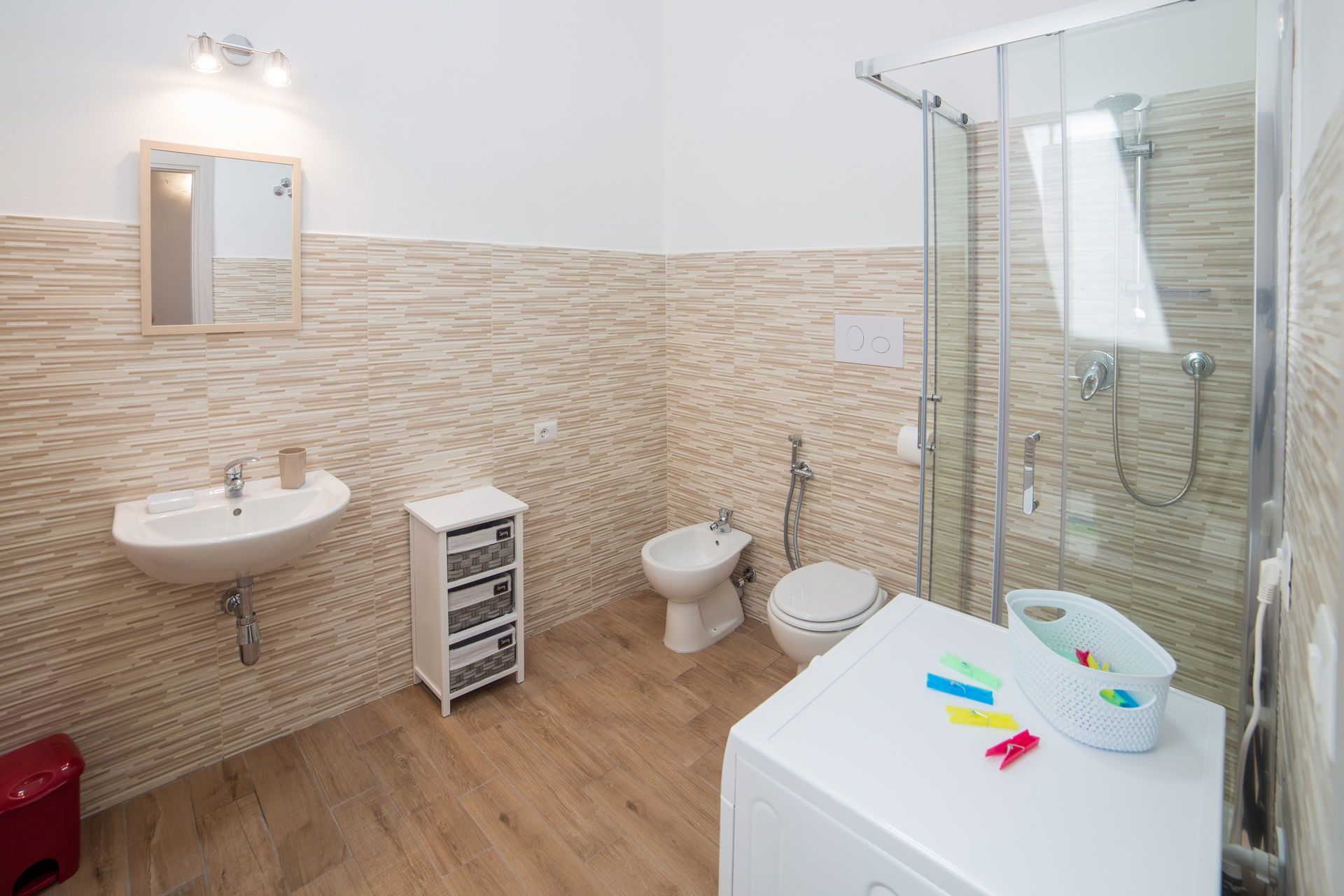 Un bagno moderno con lavandino, bidet, WC e box doccia in vetro.