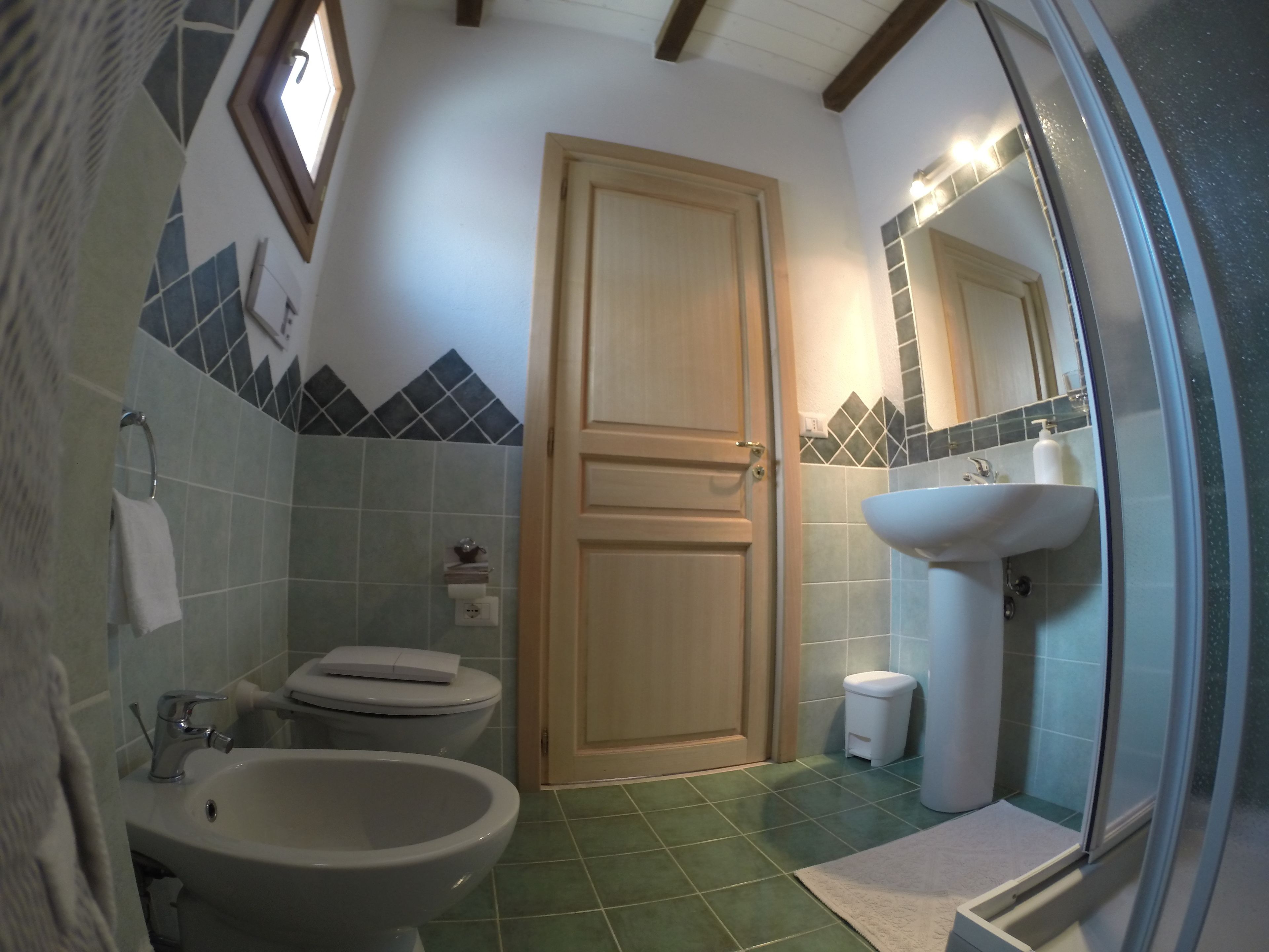 A bathroom with a toilet, sink, and mirror.
