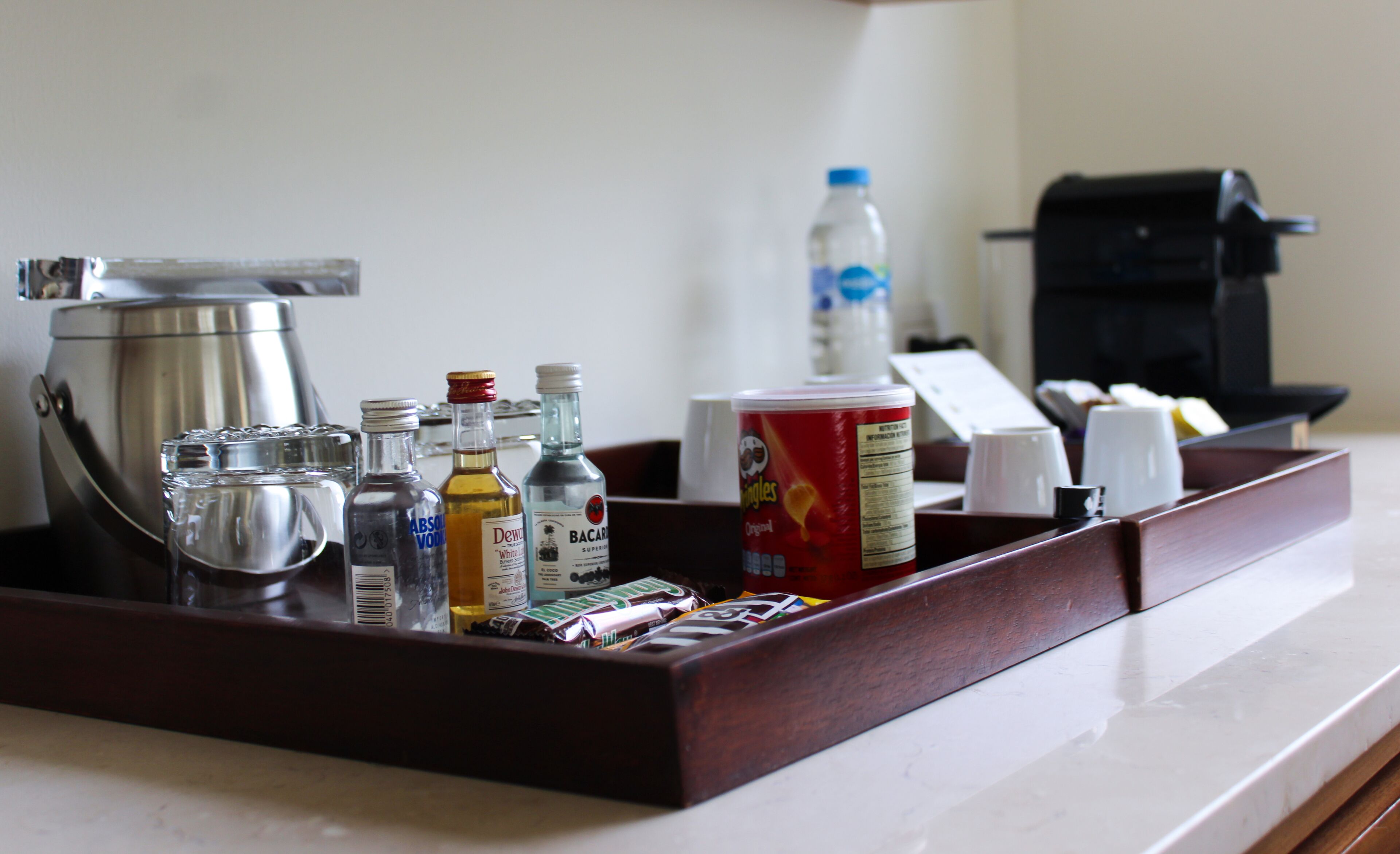 A tray with various items including bottles, a can, and a coffee maker.