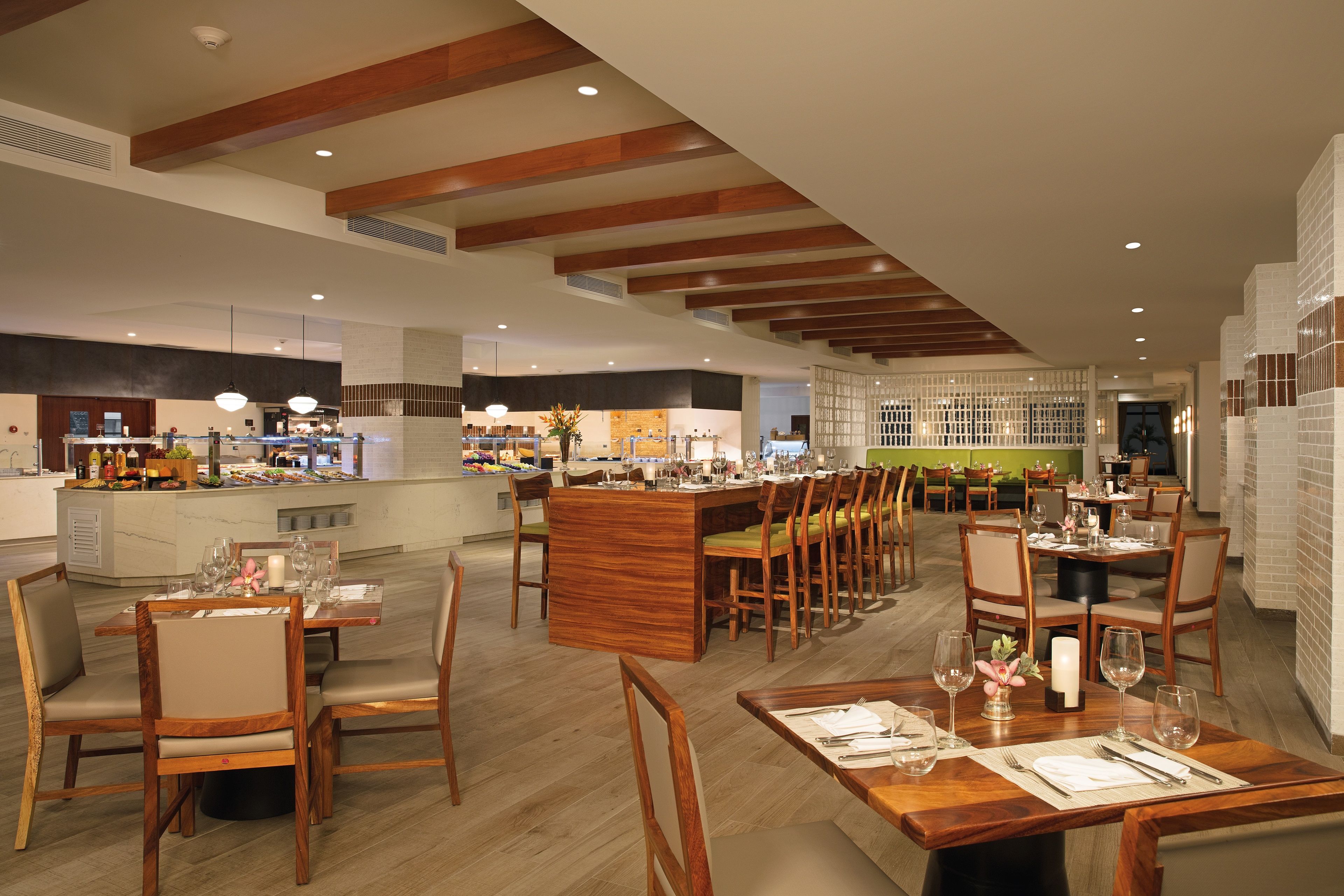 Een ruim restaurant met houten meubels en een bar in het midden.
