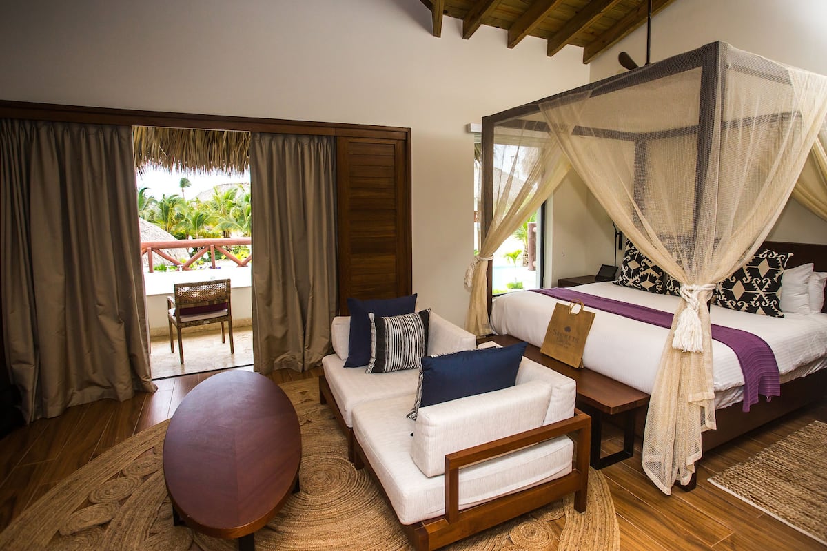 A bedroom with a bed, a sofa, a table, and a chair.
