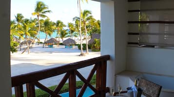 Un balcón con vista a una playa, palmeras y una piscina.