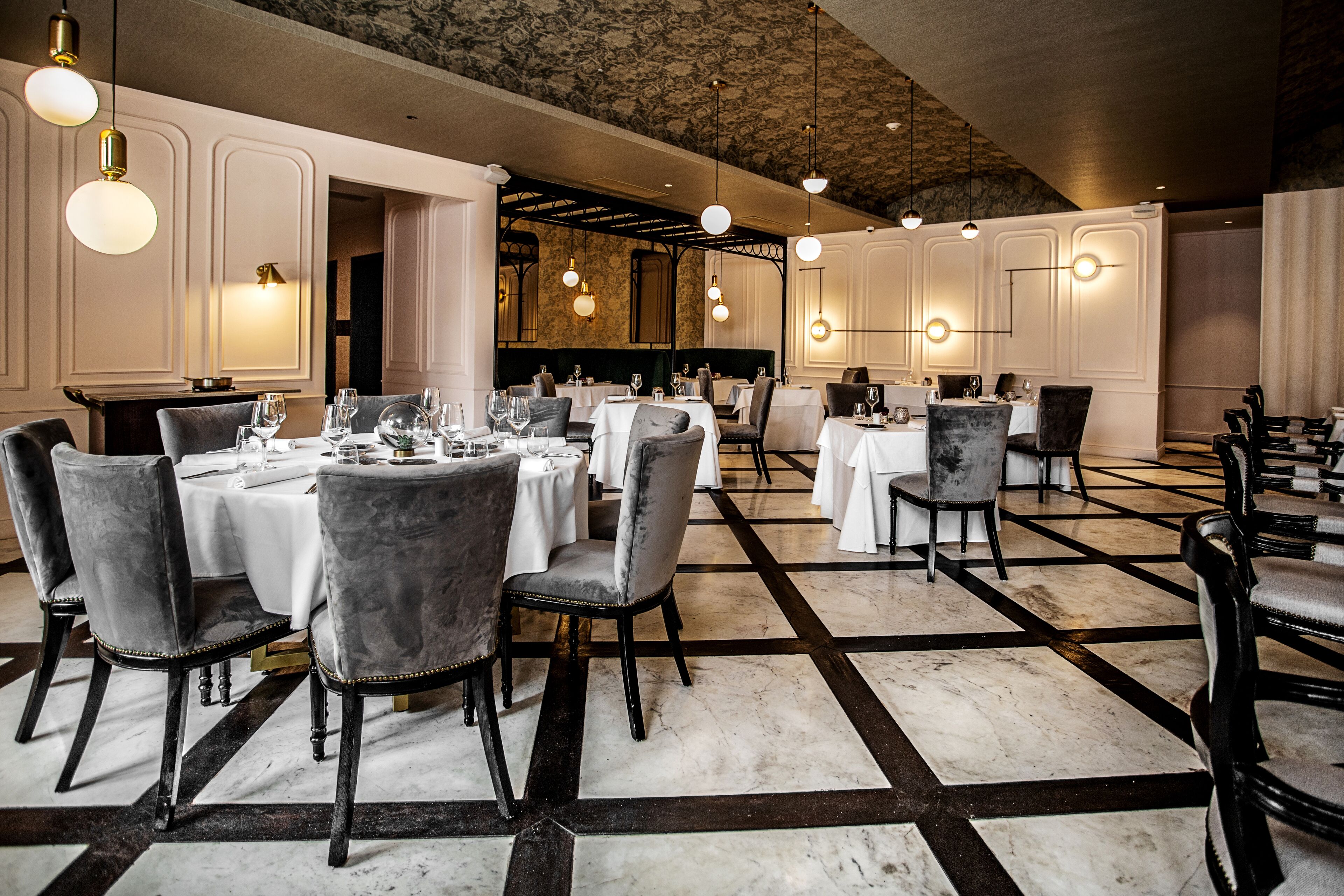 Un restaurant doté de nombreuses tables, de chaises et de luminaires suspendus.