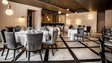 Un restaurant doté de nombreuses tables, de chaises et de luminaires suspendus.