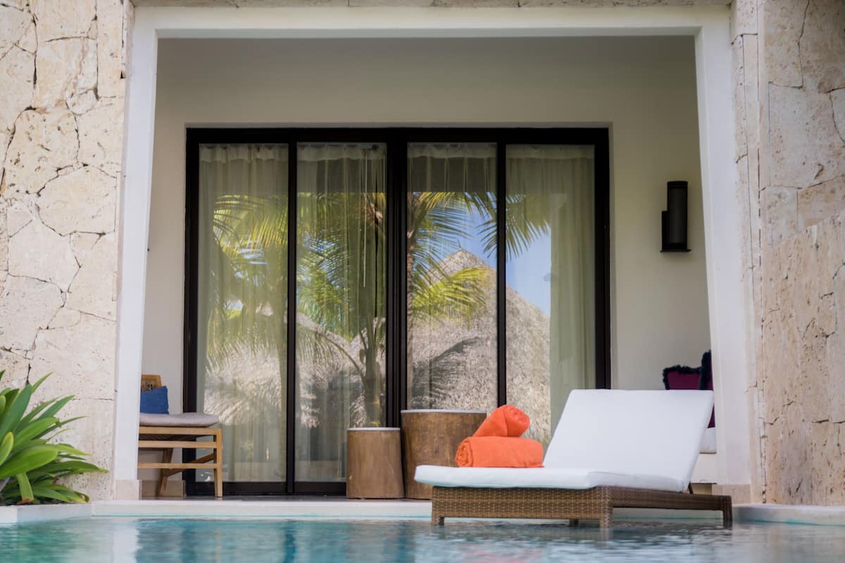 A poolside area with a lounge chair, a small table, and a potted plant.