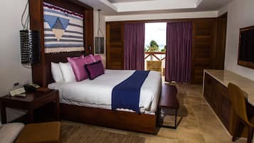 Habitación de hotel con una cama grande, un escritorio y vista al océano a través de la ventana.