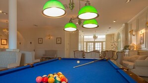 A pool table with colorful balls, a green overhead light fixture, and a billiard cue. - Riviera Airport Modlin (OLSZEWNICA NOWA)