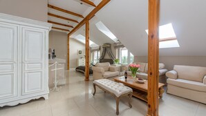 A spacious loft with high ceilings, exposed wooden beams, and a skylight. There is a large white cabinet, a beige sofa, and a wooden bench. - Riviera Resort Modlin Airport (gmina Wieliszew)
