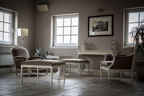 A room with a dining table, two chairs, a bench, a lamp, and a framed picture on the wall. - Riviera Resort Modlin Airport (gmina Wieliszew)
