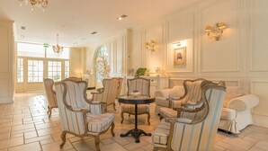 A spacious lobby with classic furniture, a round table, and elegant wall sconces. - Riviera Resort Modlin Airport (gmina Wieliszew)