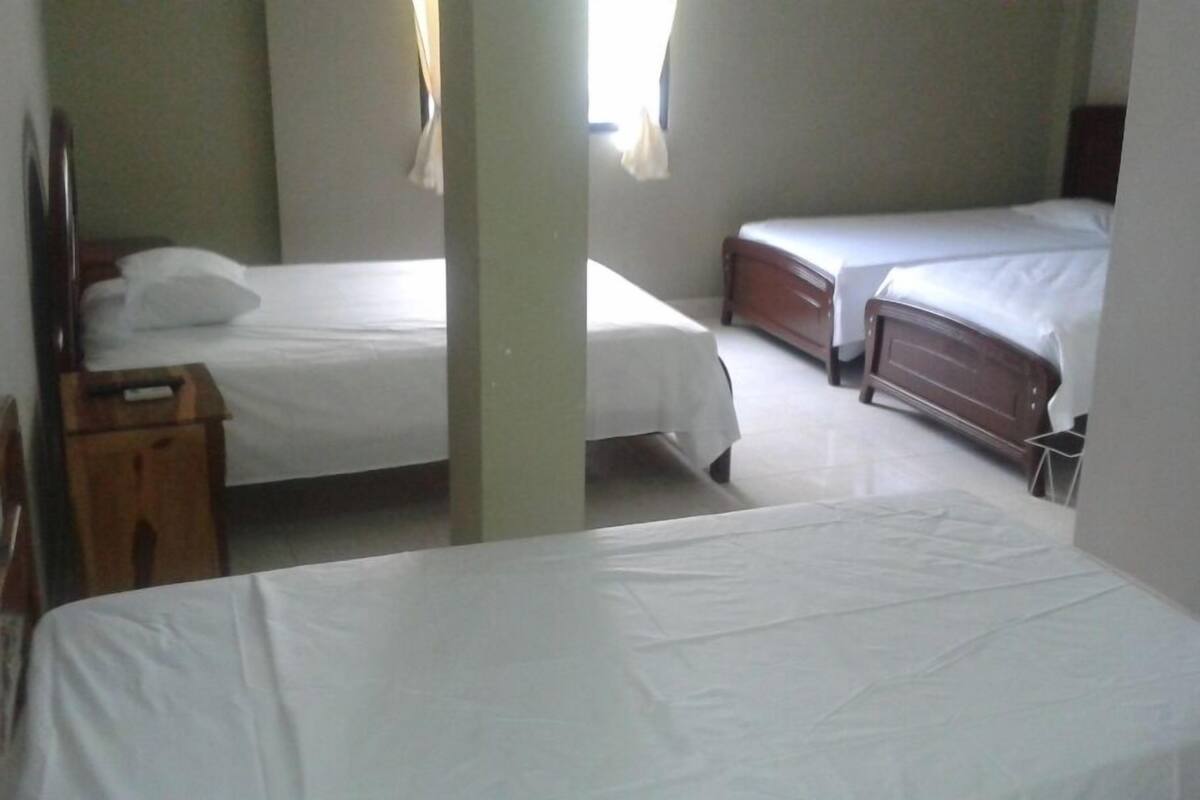 A room with two single beds, a wooden nightstand, and a small table.