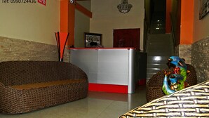 A reception area with wicker furniture, a reception desk, and a decorative fish sculpture. - Hotel Rio Guayas (Guayaquil)