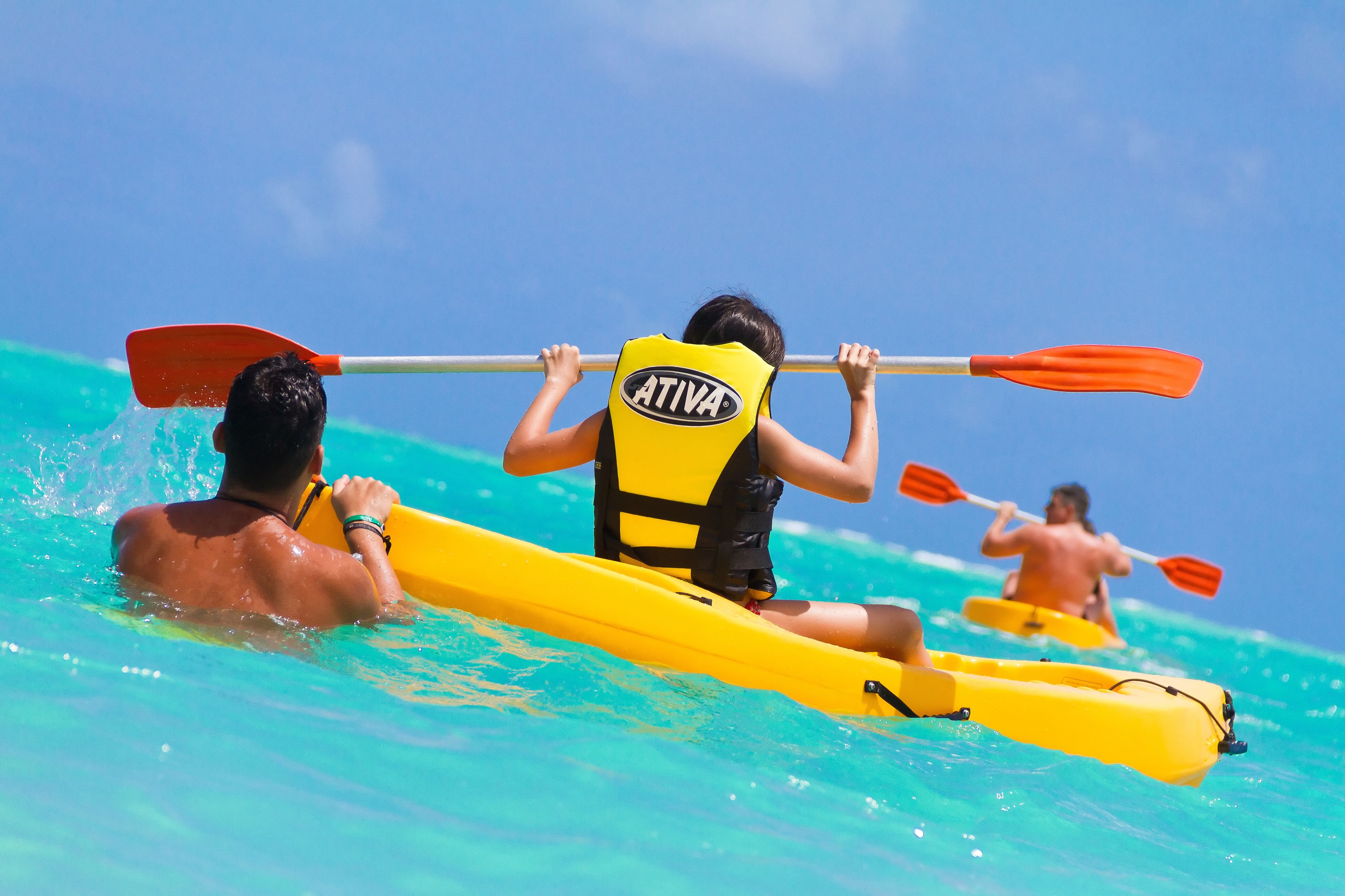 A group of people kayaking in clear blue water.