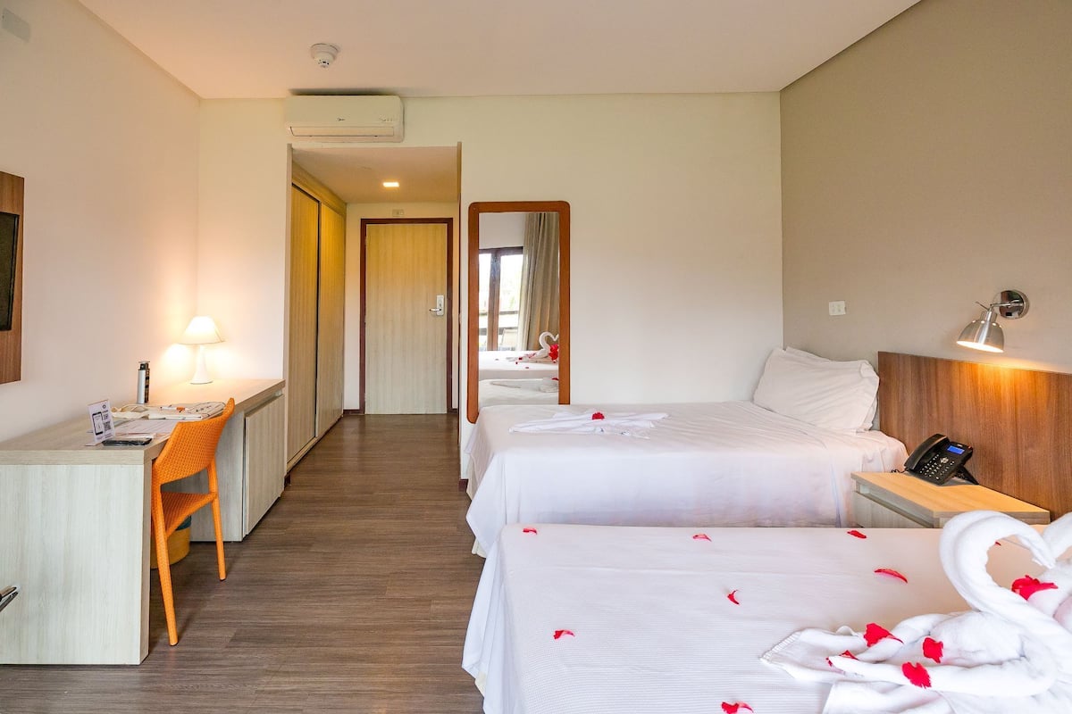 Een hotelkamer met twee bedden, een bureau, een stoel en een spiegel.