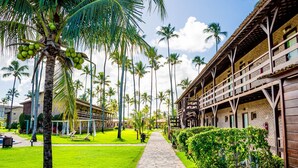 Un resort con un sendero pavimentado, palmeras y un edificio con varios balcones.