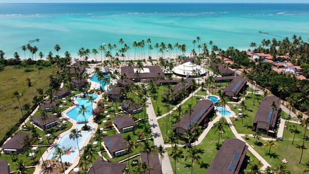 Vista aérea de un resort con múltiples piscinas, palmeras y vistas a la playa.