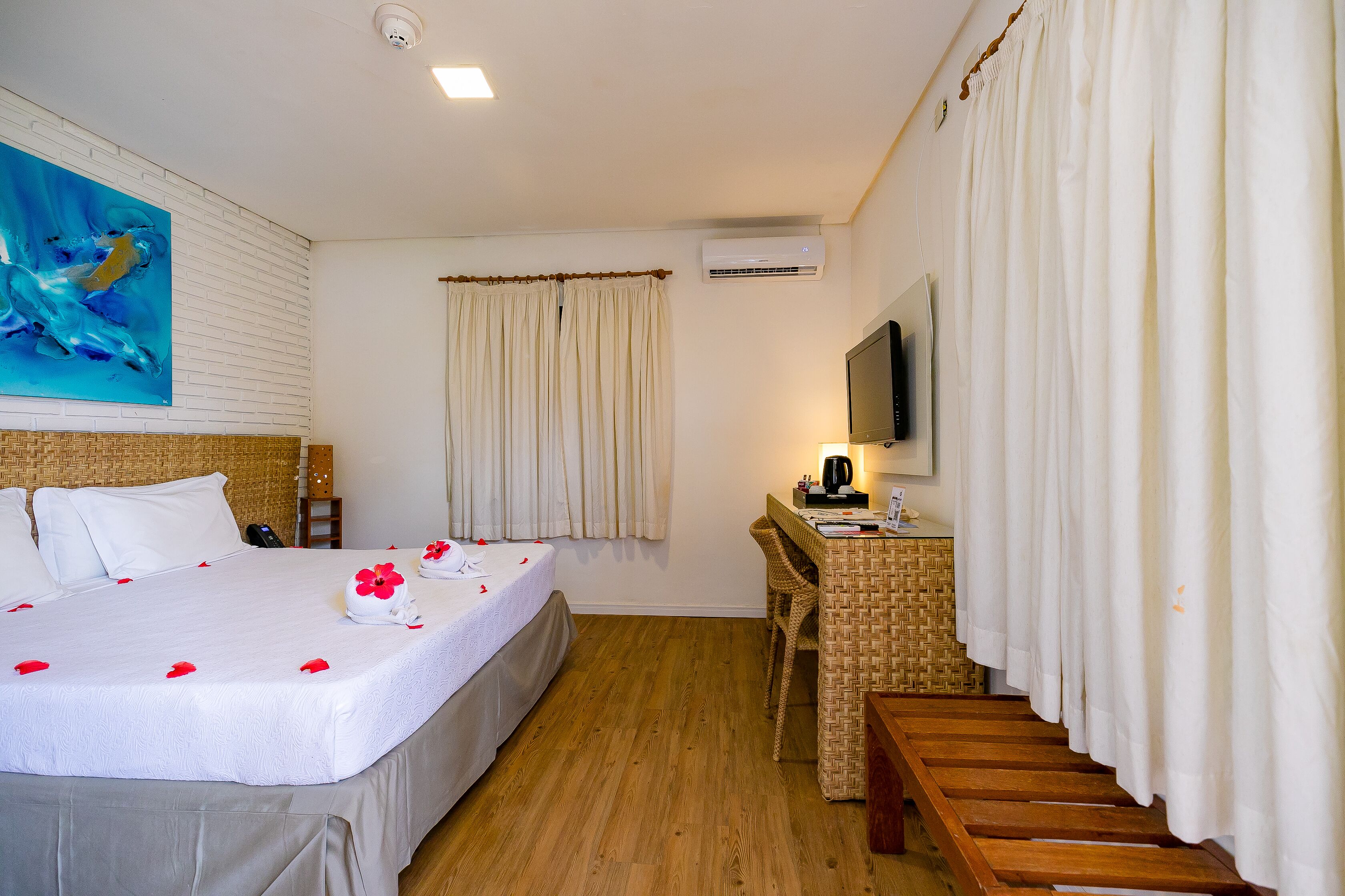 Una camera d'albergo con un letto, una scrivania, una sedia, una televisione e un quadro appeso al muro.
