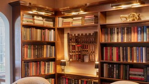 A library with two armchairs, bookshelves, and a chessboard. - Wickwood Inn (Saugatuck)