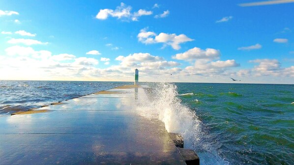 A pier extending into the sea with waves crashing against it.