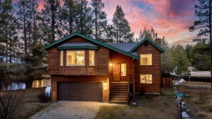 Een houten chalet met garage, een overdekte veranda en uitzicht op een meer.