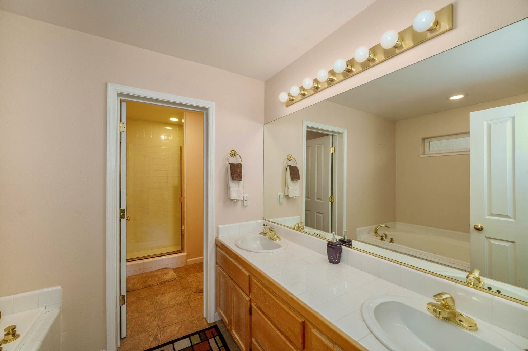Une salle de bain avec deux lavabos, un grand miroir et une douche.