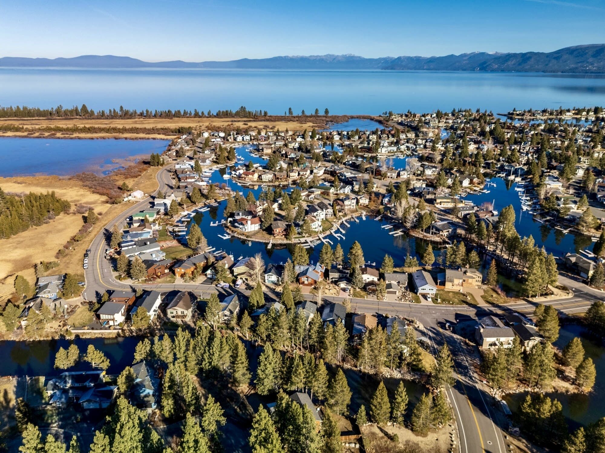 Vue aérienne d’un quartier résidentiel avec des maisons, des routes et un lac.