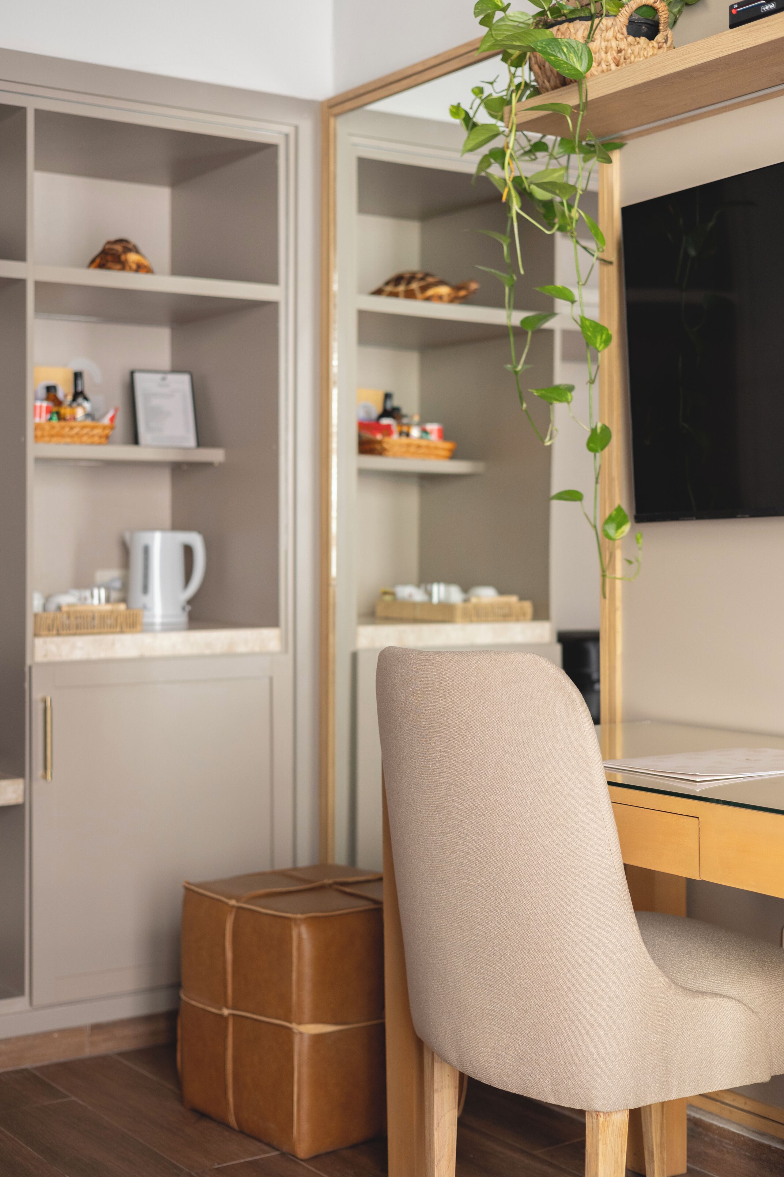 Une pièce comprenant un bureau, une chaise, une bibliothèque, une machine à café et une plante.