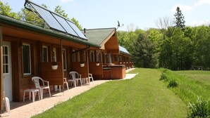 A row of wooden cabins with solar panels, outdoor seating, and a grassy area. - Quiet Bay: Lakeside Escape (Magnetawan)