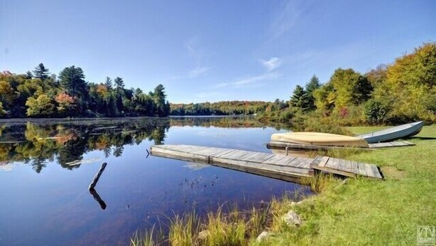 A calm lake with a wooden dock and a boat. - Quiet Bay: Lakeside Escape (Magnetawan)