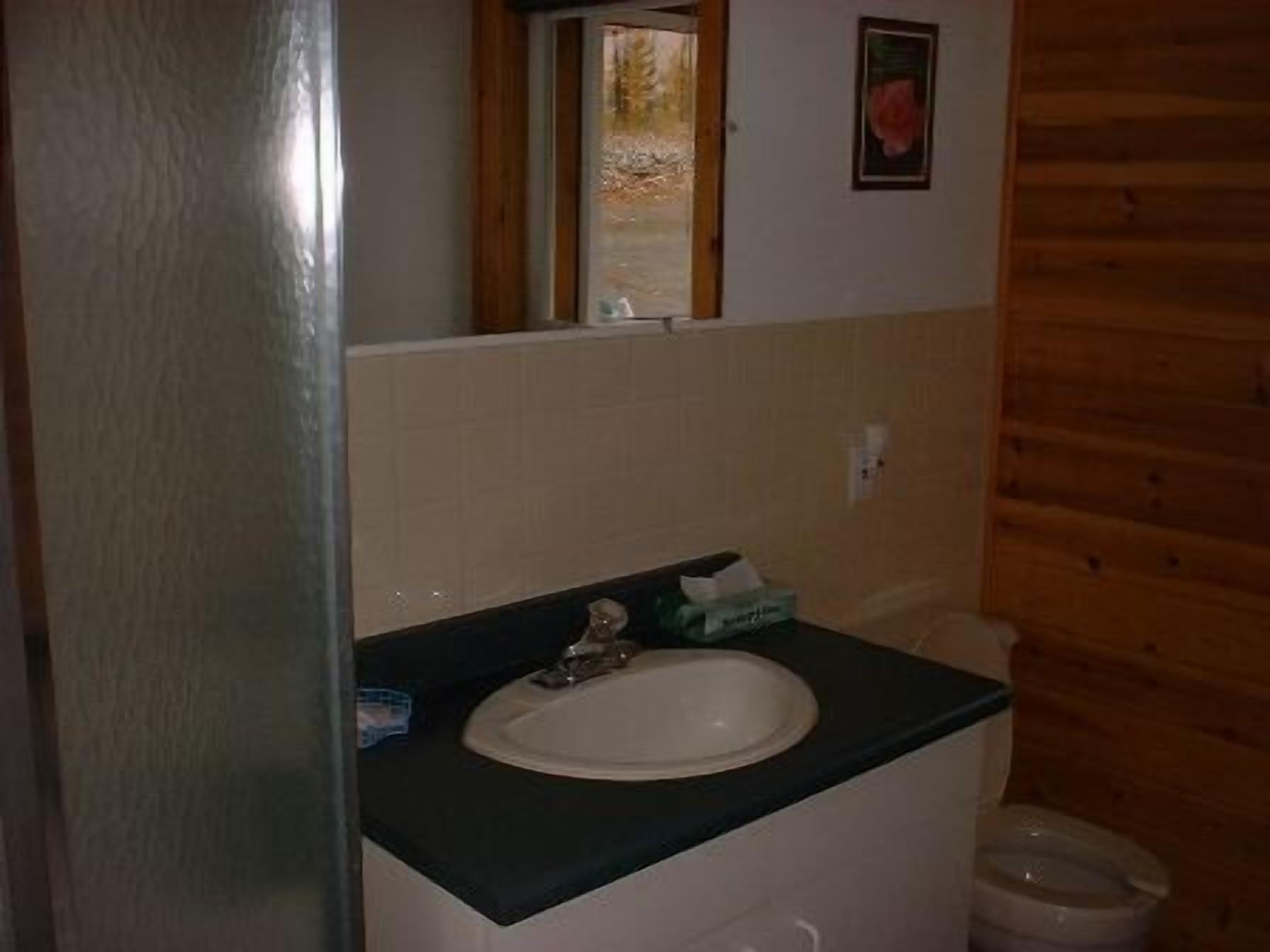 A bathroom with a white sink, a mirror, and a wooden wall.