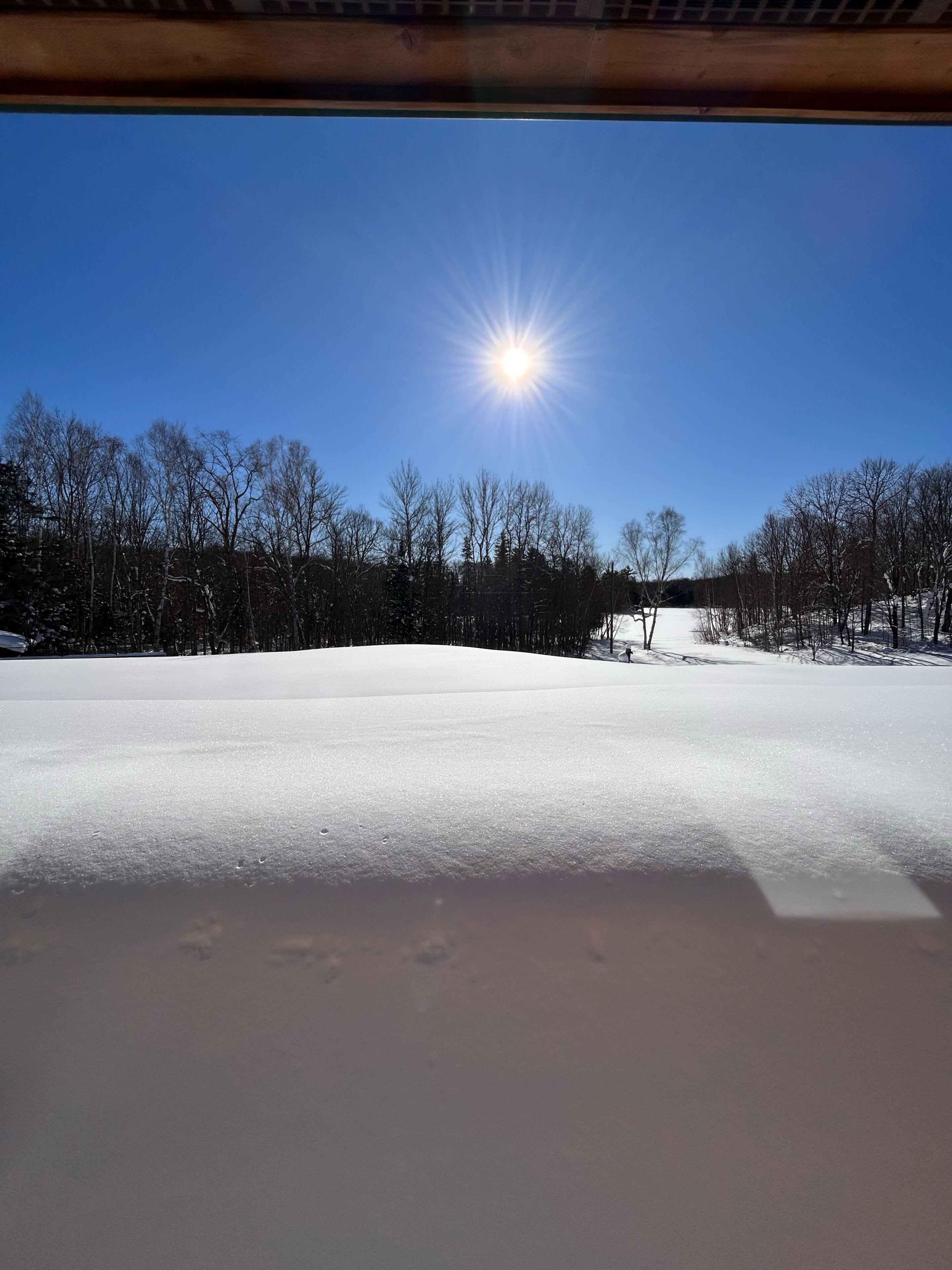 A snowy landscape with a clear sky and a bright sun.