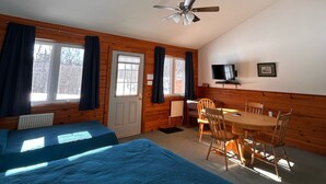 A room with two beds, a dining table with chairs, a ceiling fan, and a television on the wall. - Quiet Bay: Lakeside Escape (Magnetawan)