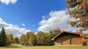 A grassy pathway leading to a wooden building with a sloped roof, surrounded by trees with autumn foliage. - Quiet Bay: Lakeside Escape (Magnetawan)