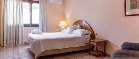 A neatly arranged bedroom with a bed, bedside table, lamp, and a framed picture on the wall.