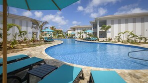 A swimming pool with lounge chairs and umbrellas, surrounded by palm trees and a clear sky. - Habitat Bonaire (Kralendijk)