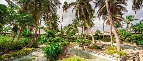 A tropical resort with palm trees, a water feature, and a wooden deck.