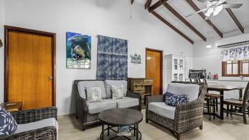 Un espacio de sala acogedor con muebles de mimbre, una mesa de centro redonda y una zona de cocina con una mesa de comedor y sillas.