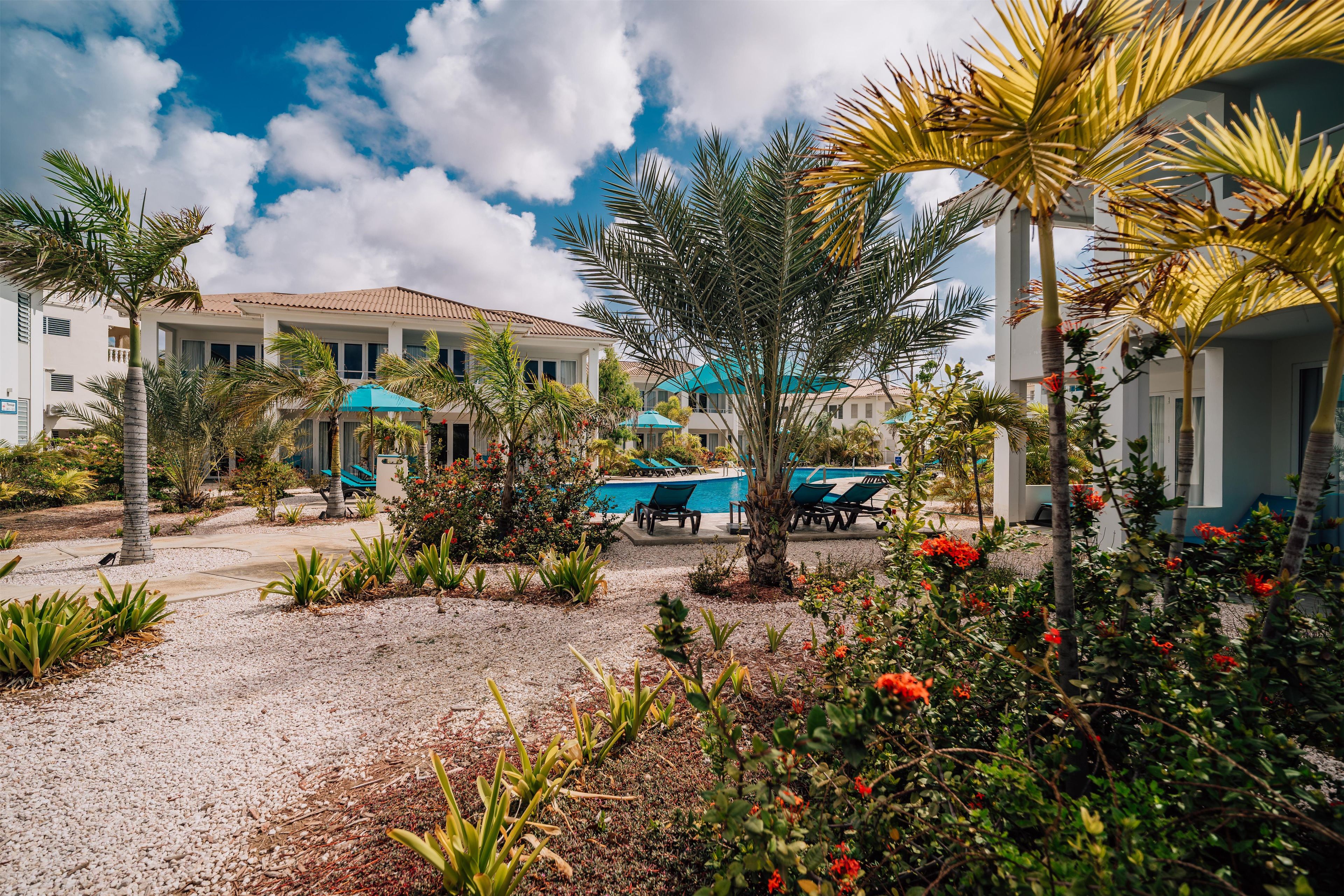 Un resort con piscina, palmeras y un edificio con techo de tejas.
