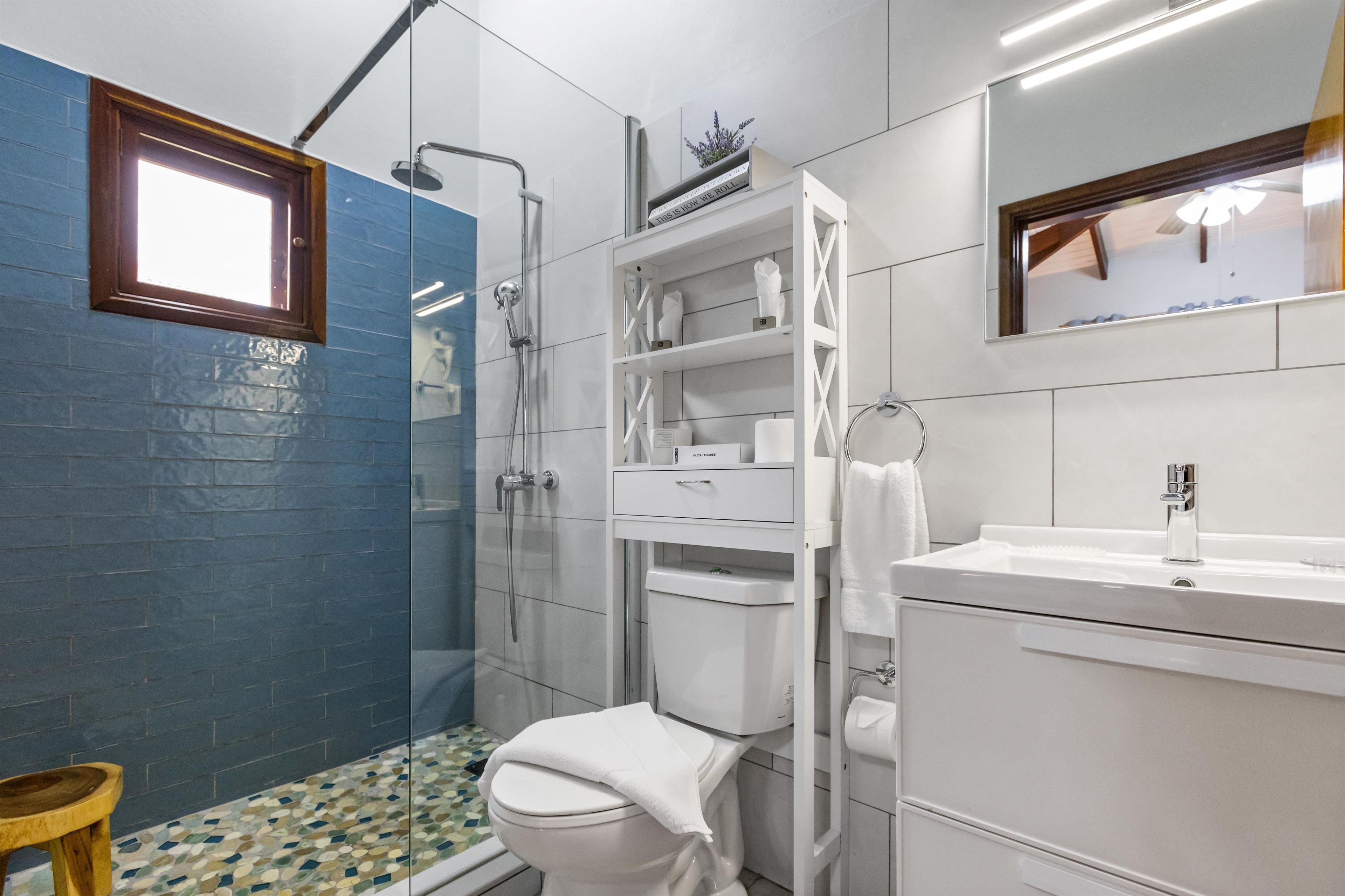 Een moderne badkamer met een douchecabine van glas, een toilet en een wastafel met spiegel.