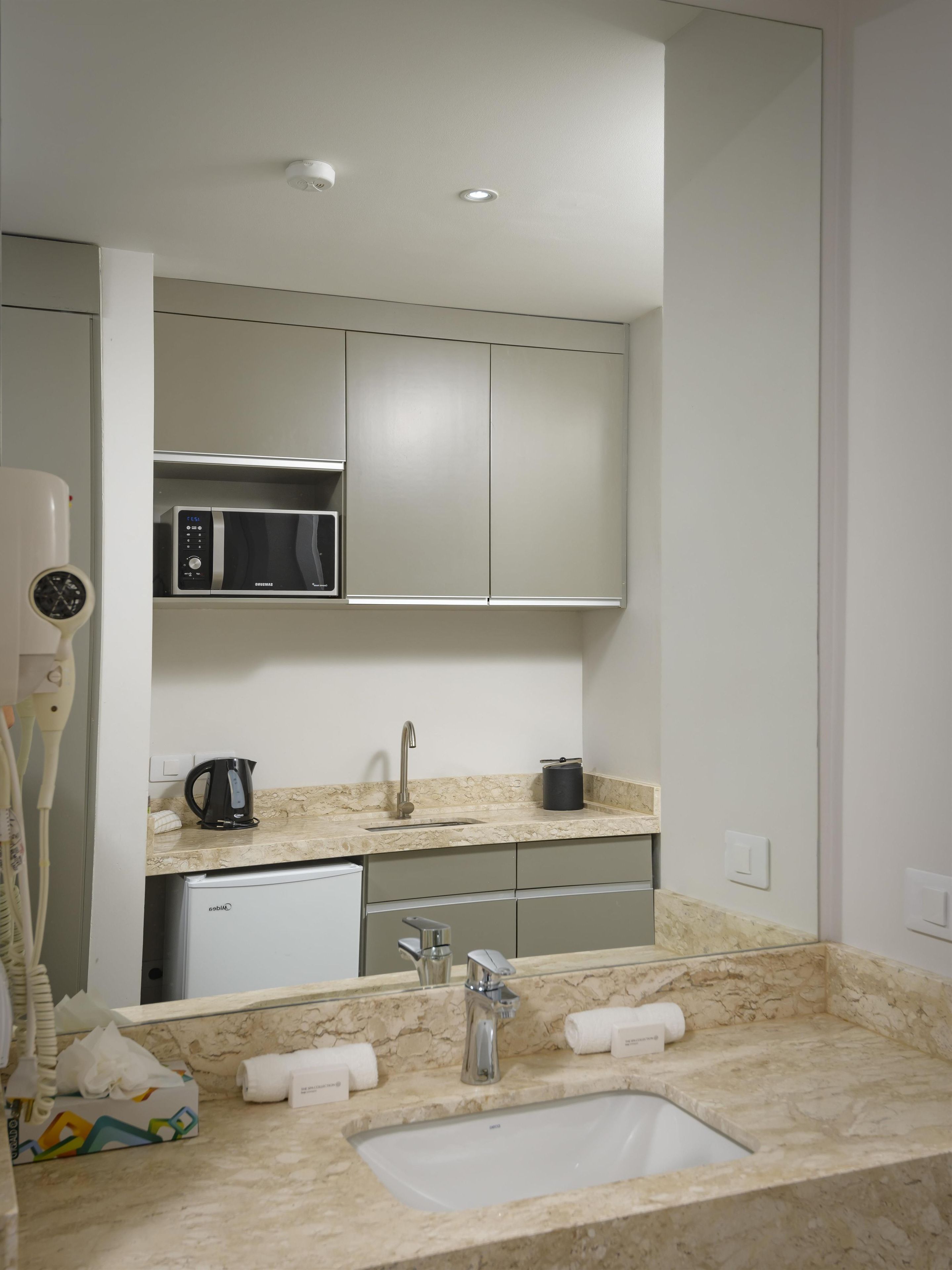 A modern kitchen with a built-in microwave, a coffee maker, and a sink with a marble countertop.