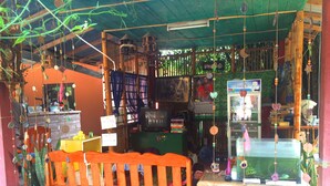 A small shop with a wooden bench, shelves with various items, and a television. - Rainbow House (Pai)