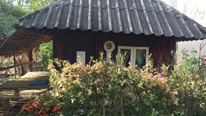 A rustic house with a corrugated metal roof, a wooden door, and a number '9' sign. - Rainbow House (Pai)