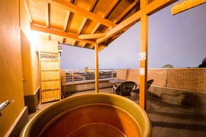 Una terraza en la azotea con vistas a un horizonte urbano, una pérgola de madera y un área de estar con mesa y sillas.