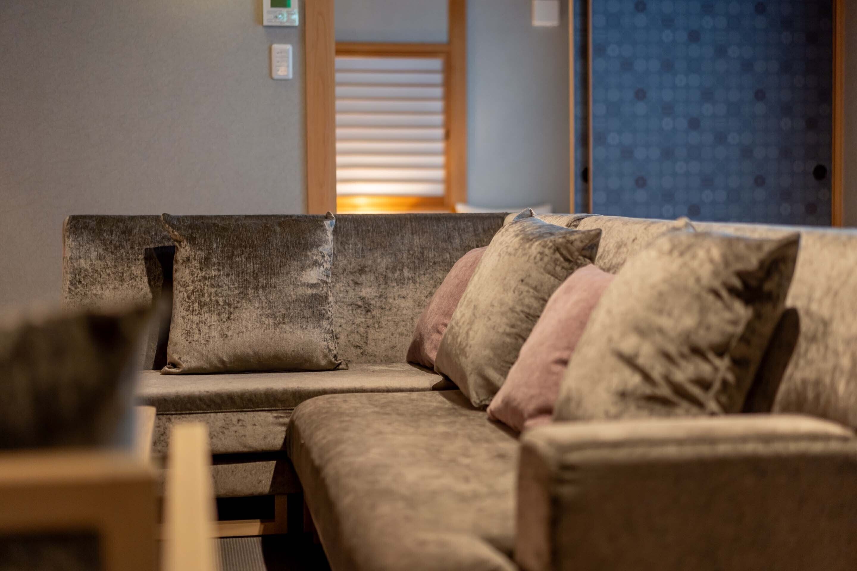 Un rincón acogedor con sofá y sillones, una puerta de madera y un muro decorado.