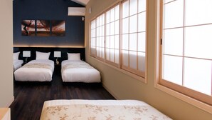 A hotel room with two single beds, a large window with a view, a painting on the wall, and a ceiling with exposed beams. - RESI STAY Fuyacho (Kyoto)
