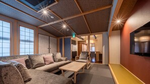 A modern interior with a sofa set, a table, and a TV mounted on the wall. - RESI STAY Fuyacho (Kyoto)