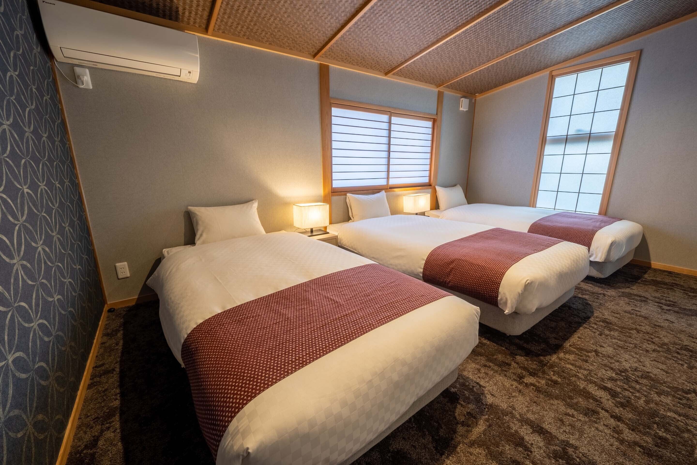 A hotel room with two beds, a large window, and a ceiling fan.