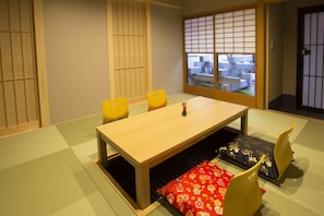 A traditional Japanese room with tatami flooring, a low table, and yellow chairs. - RESI STAY Fuyacho (Kyoto)
