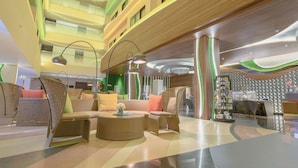 Un hall d'entrée moderne avec un plafond haut, de nombreux étages et un comptoir d'accueil agrémenté d'une bibliothèque.